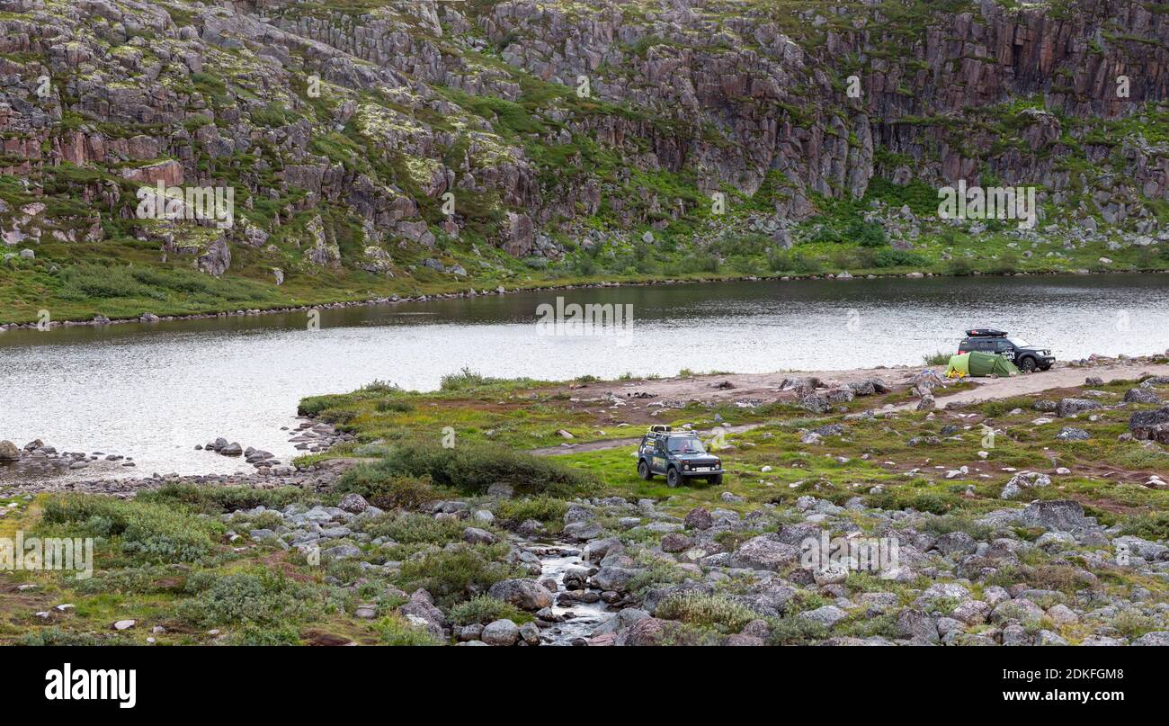 Kola Peninsula, Russia - August 26, 2018: Parking of tourists traveling by car by the lake in the tundra of the Kola Peninsula near the coast of the B Stock Photo