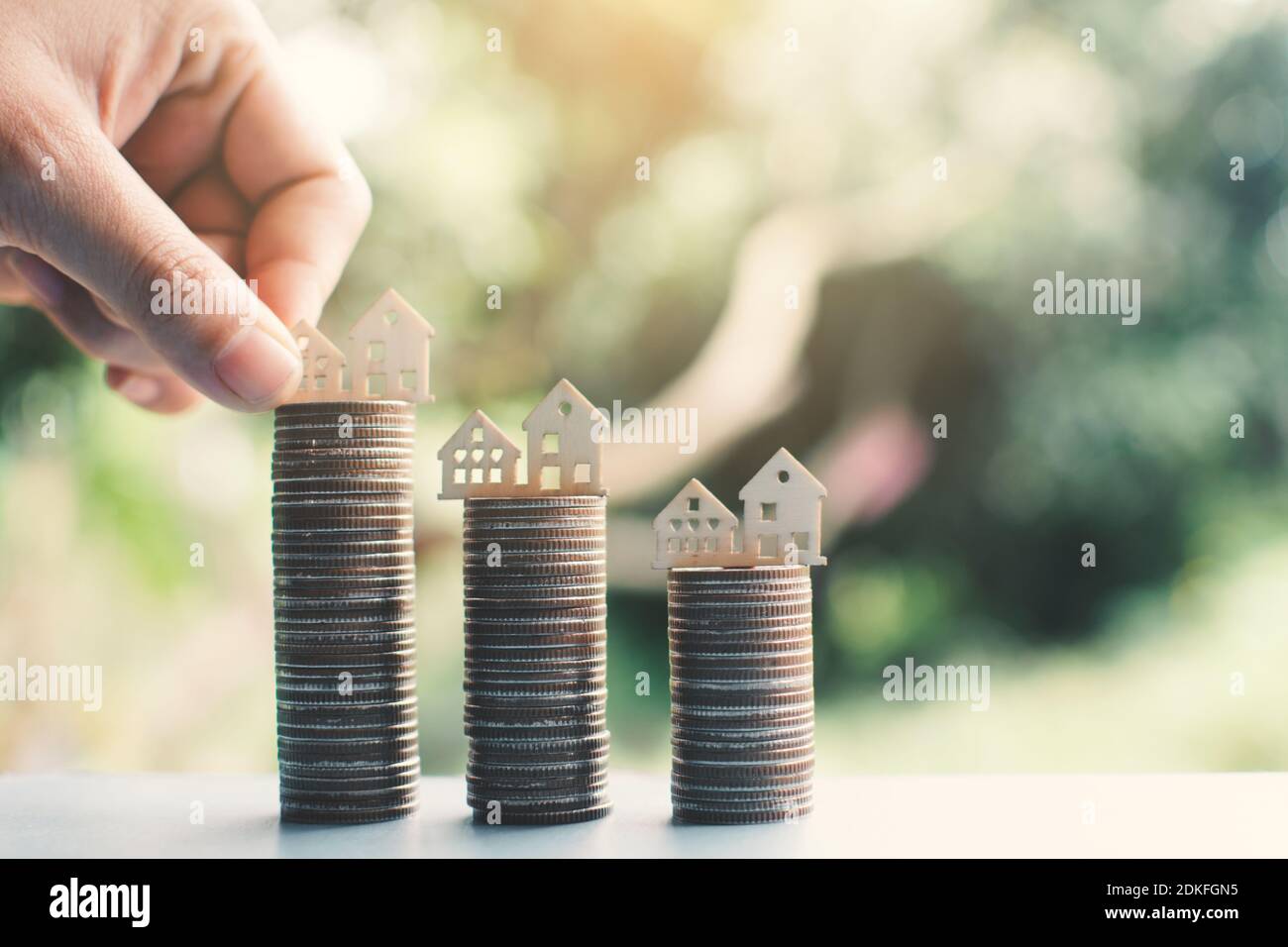 Cropped Hand Putting Model Homes On Stacked Coins Stock Photo