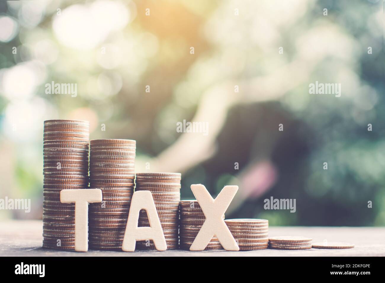 Close-up Of Tax Text With Coins On Wooden Table Stock Photo