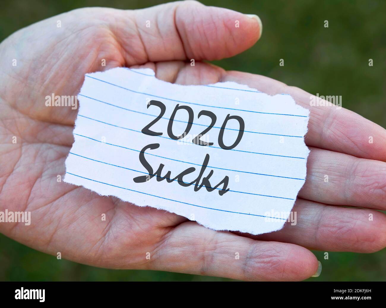 Paper note in hand, 2020 sucks. Stock Photo