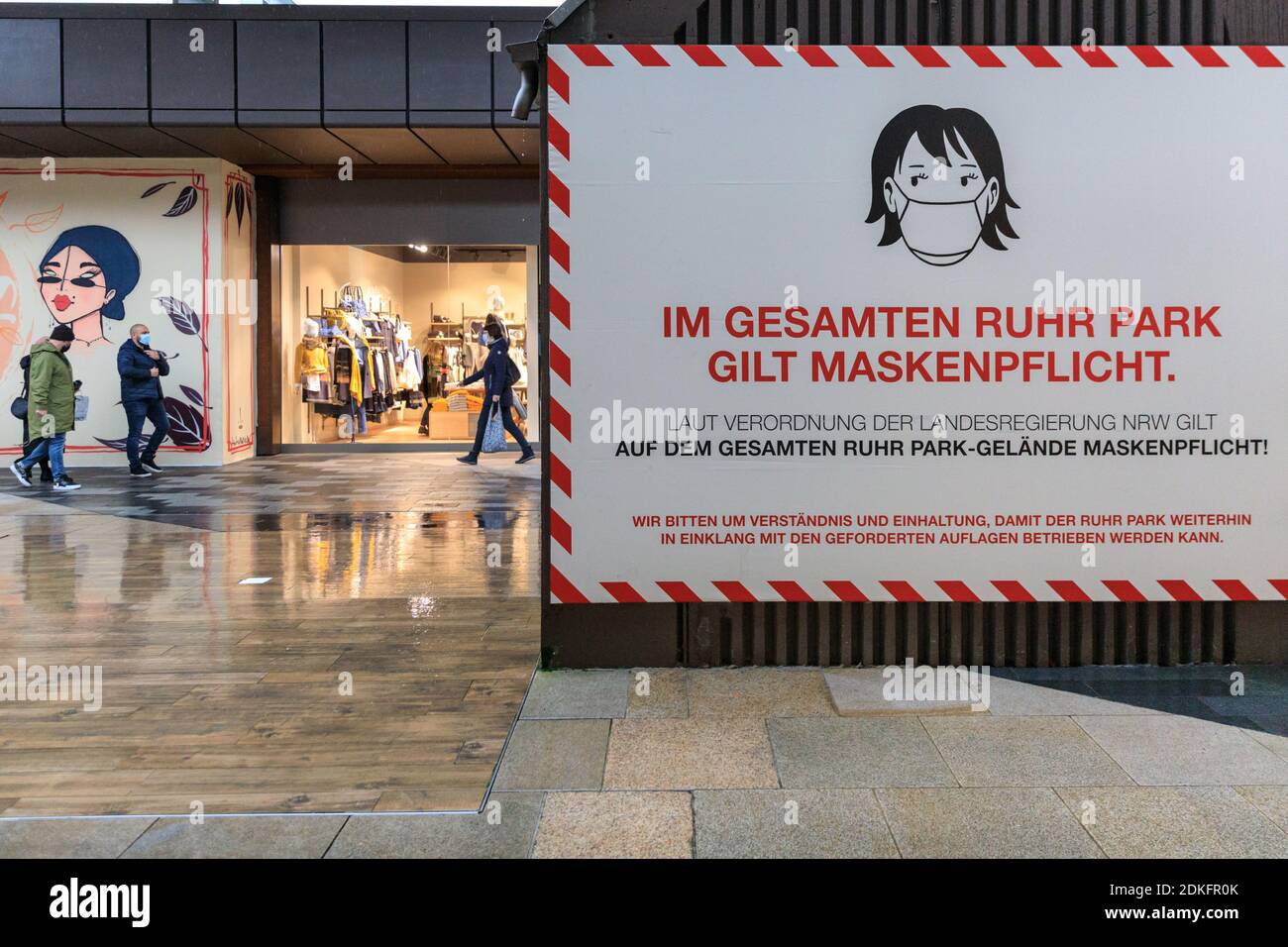 Ruhrpark Shopping Centre, Bochum, Germany, 15th Dec 2020. Large signs remind shoppers of mandatory mask wearing. The normally bustling shopping centre appears quiet on the last day before the so called 'hard lockdown' in Germany. Today was the last day retailers and services, apart from food and essential supplies, were allowed to be open before the lockdown starts tomorrow. It also includes the closure of most secondary schools, hairdressers and related services. Further measures are taken on a state by state basis.Credit: Imageplotter/Alamy Live News Stock Photo