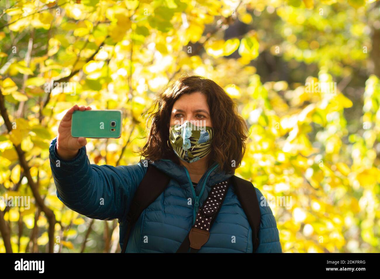 woman with a mask taking a selfie in an autumn atmosphere Stock Photo