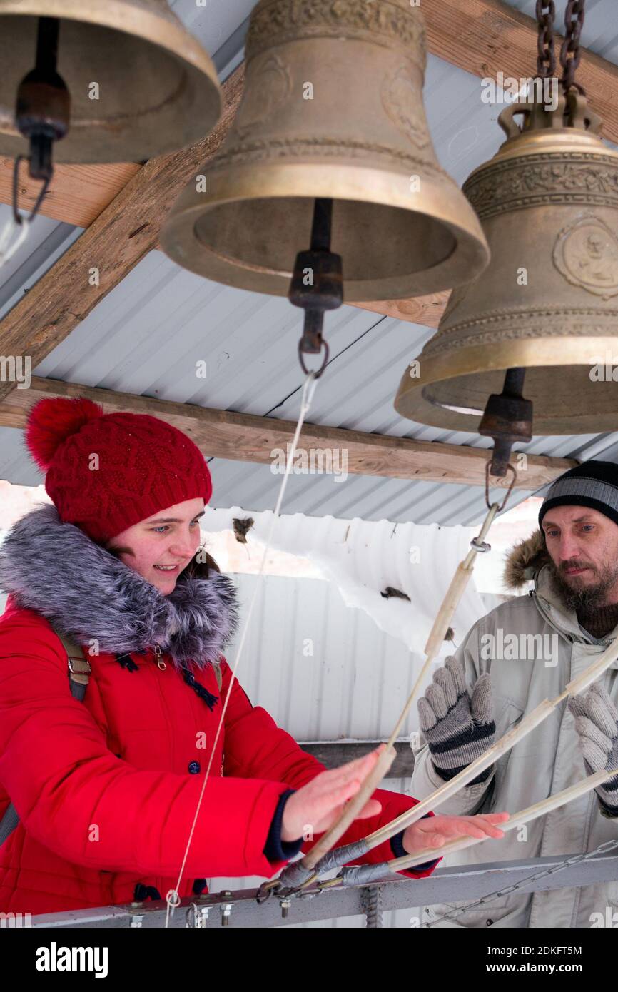 Penza, Russia - January 16, 2016: Happy smiling girl dressed in red girl takes a lesson of bell ringing on the open in winter day in Penza city, Russi Stock Photo