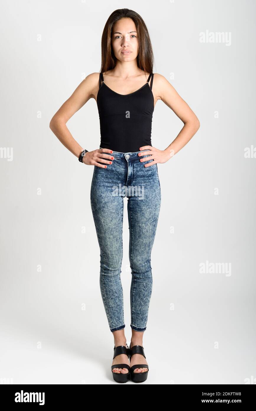 Young woman wearing black tank top and blue jeans on white background.  Studio shot Stock Photo - Alamy