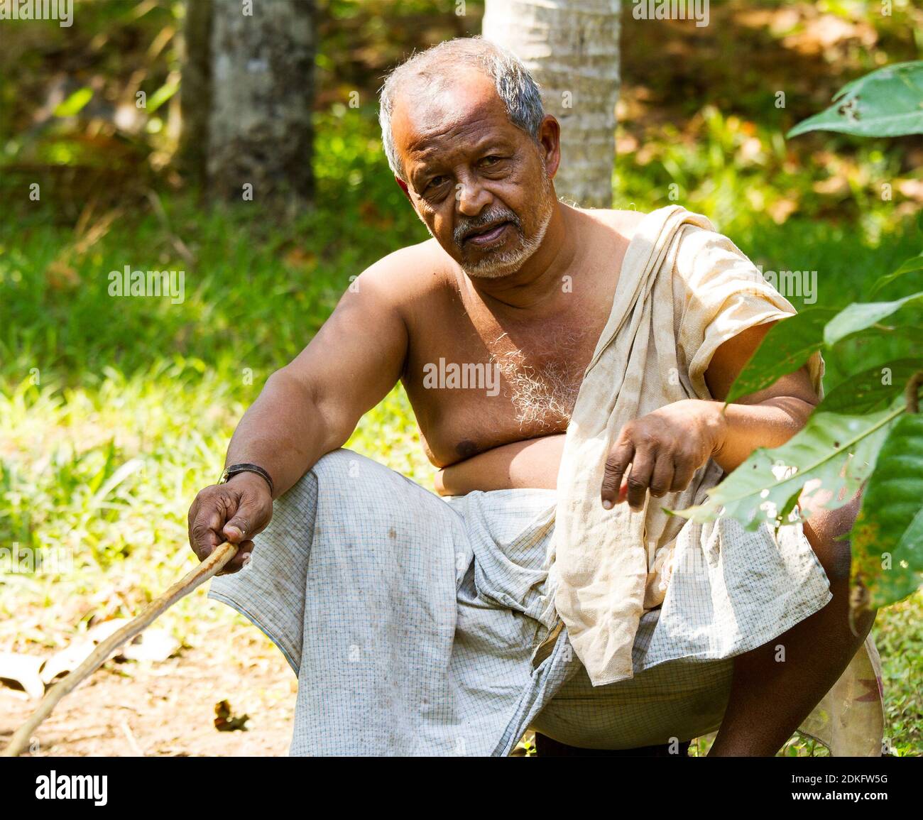 Kerala backwaters, India - Jan 22, 2012: Tanned old Indian fishing with home-made fishing rod at the hot sunny day in Kerala backwaters, Southern Indi Stock Photo