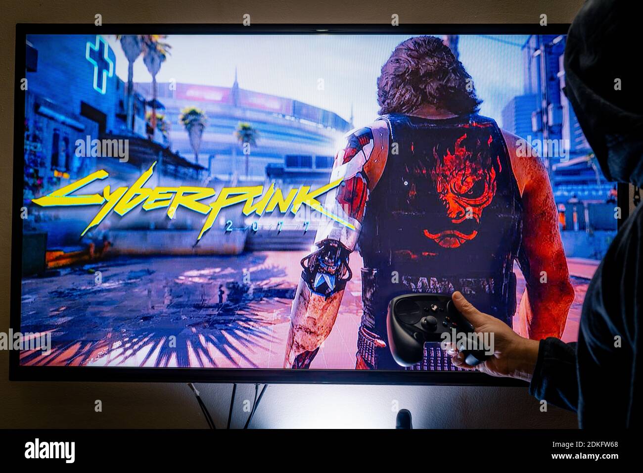 Woman holding a steam controller and playing popular video game Cyberpunk  2077 on a television and PC Stock Photo - Alamy