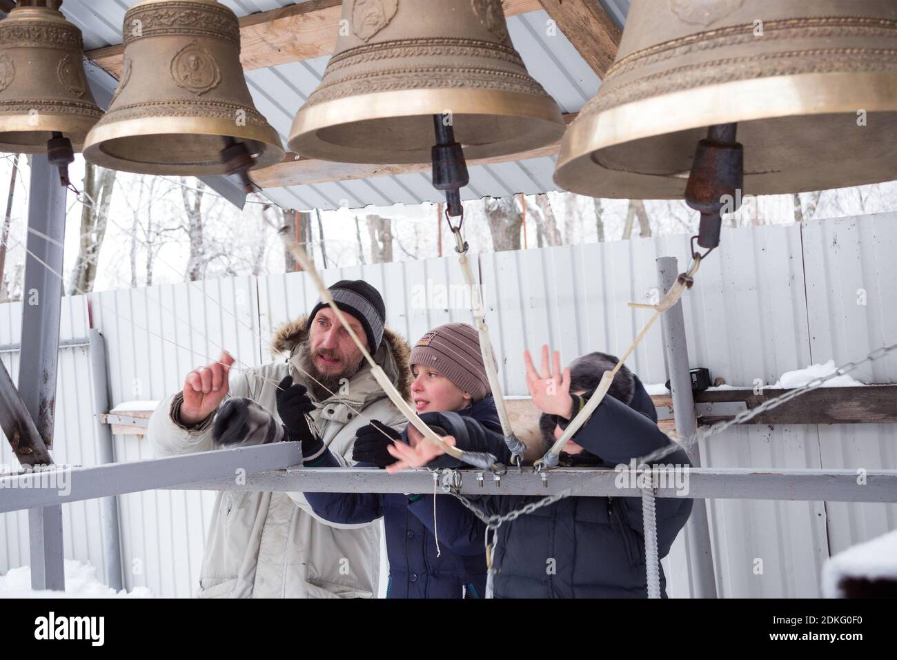Penza, Russia - January 16, 2016: The bell ringer gives two boys a lesson of bell ringing at the open bell tower of the restored cathedral on a frosty Stock Photo
