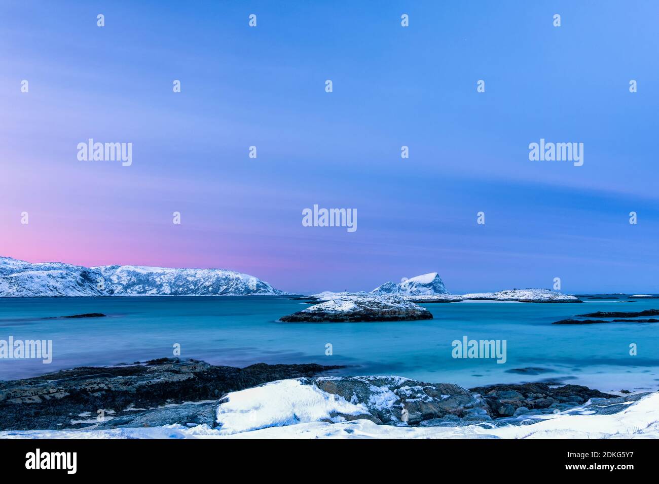 Frosty dawn on Sommaroy Island in winter with a view from the beach of the Northern European Sea and the snow-capped mountains on the horizon Stock Photo