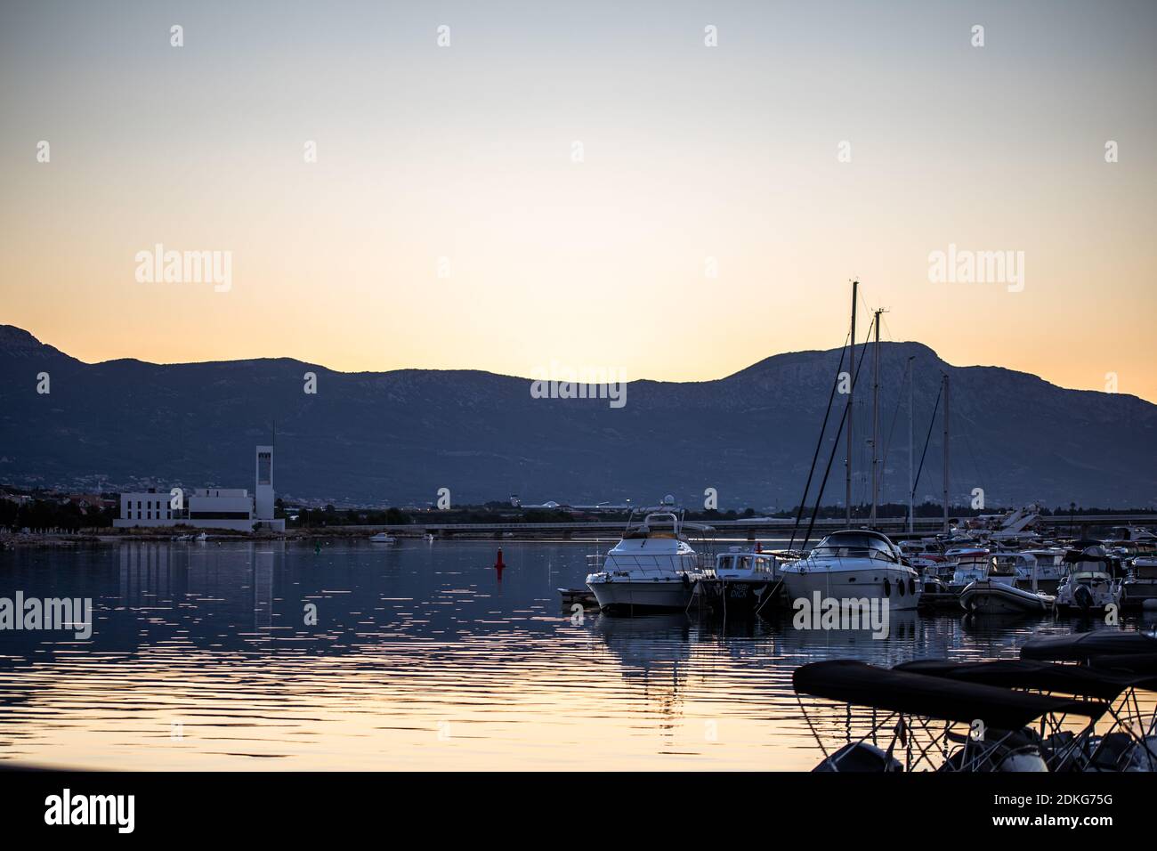 Sunrise over the water with boats in the foreground. In the background you can see the Veliki Kabal mountains. Stock Photo
