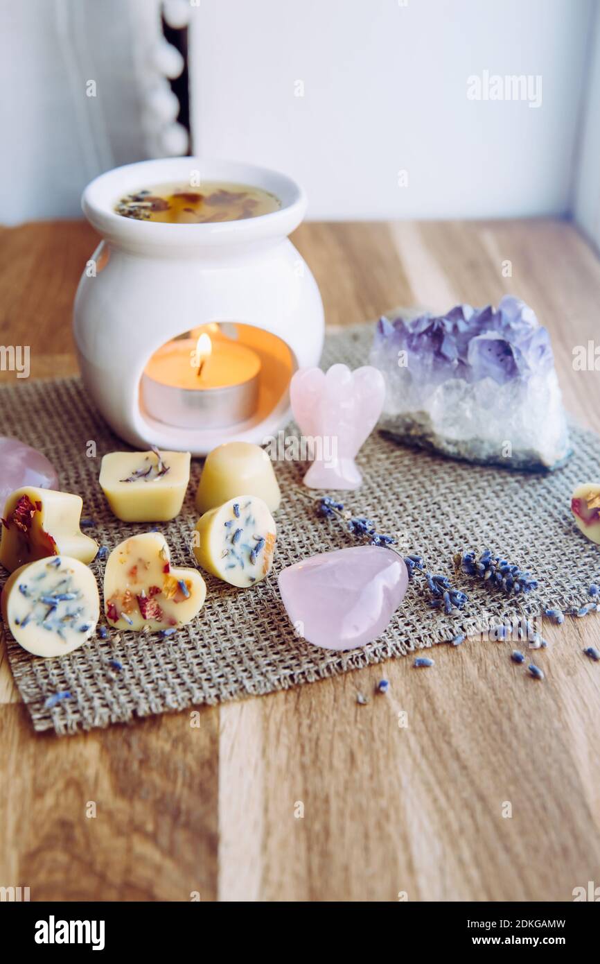 Homemade mini wax melts in aromatherapy lamp diffuser at home interior with rose quartz crystal hearts and angel for decoration on wooden window sill Stock Photo