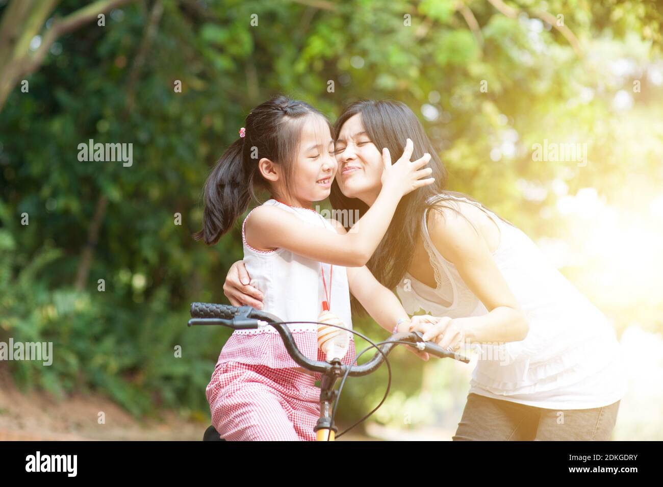 Little girl biking in the park, mother giving a goodbye kiss , Asian family  outdoor fun activity Stock Photo - Alamy