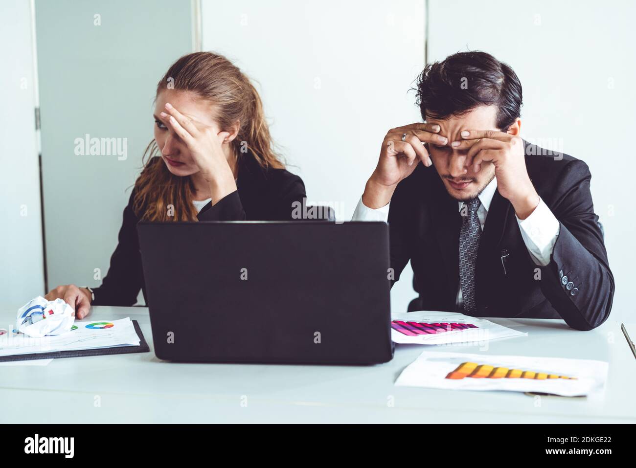 Unhappy serious businessman and businesswoman working using laptop computer on the office desk. Bad business crisis situation and bankruptcy concept. Stock Photo