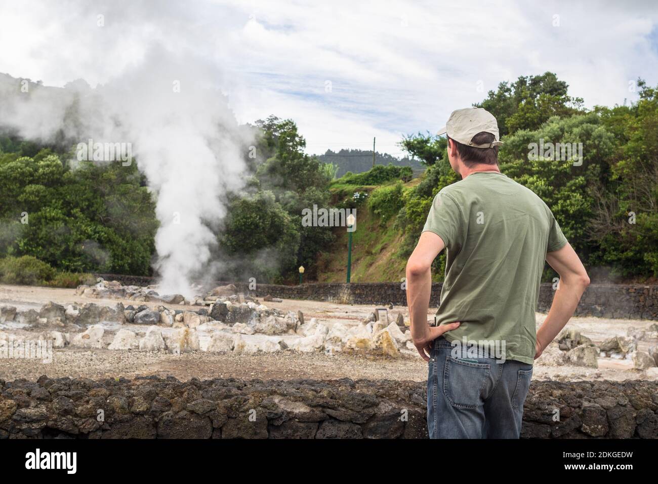 A tourist looking at boiling water and steam venting from a hot spring in the small town Furnas