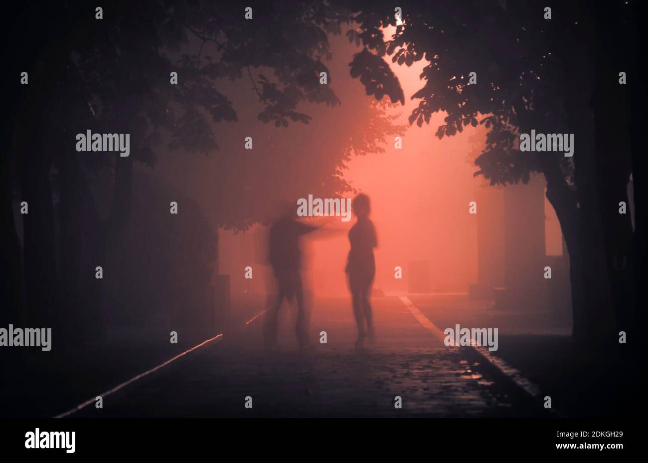 A maniac on a foggy street at night attacks a passerby. Stock Photo