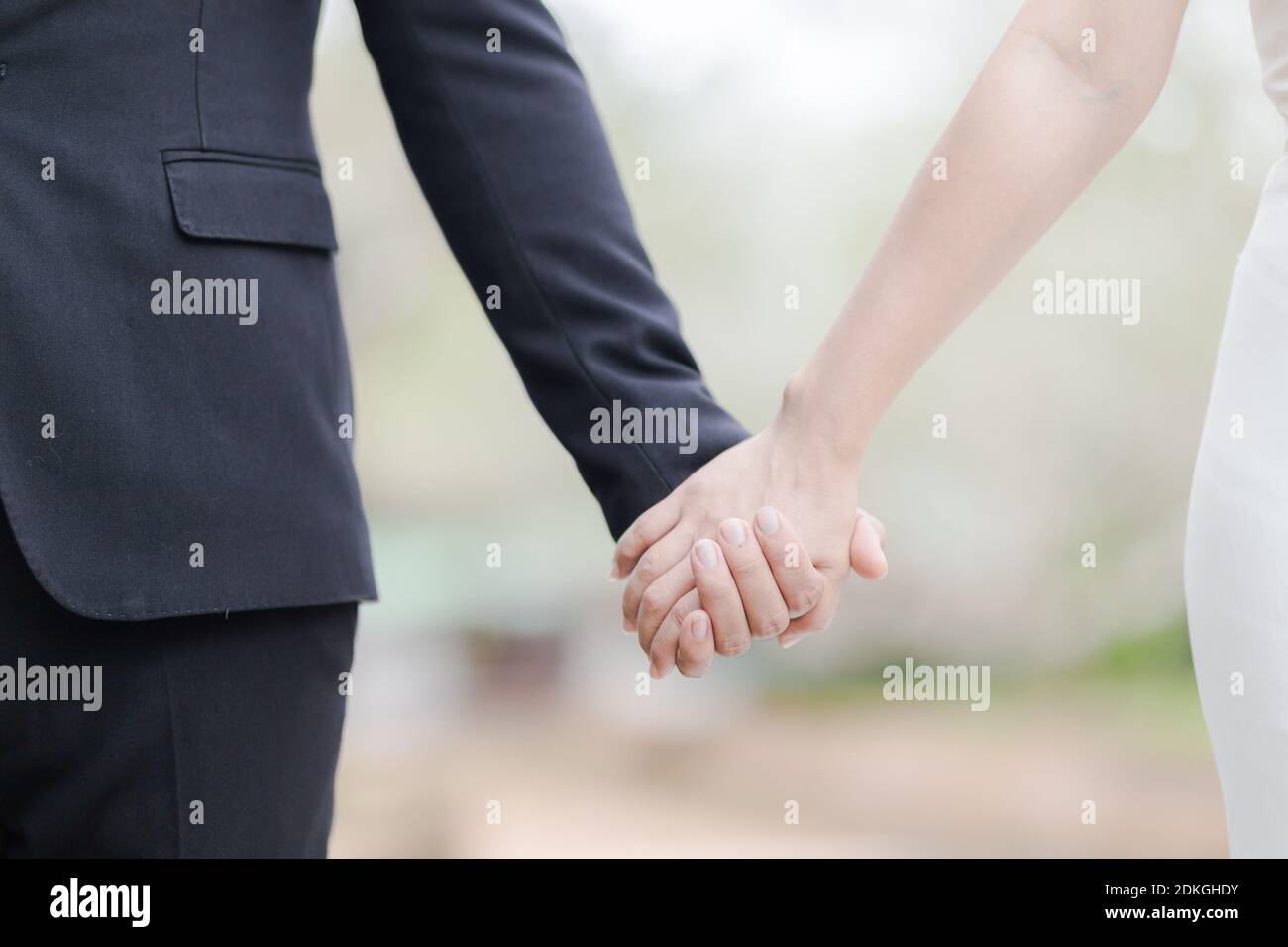 Midsection Of Newlywed Couple Holding Hands While Standing Outdoors Stock Photo