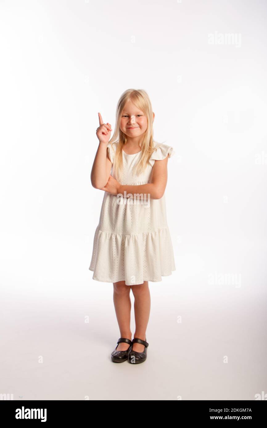 Studio portrait of fashionable little girl with index finger up. Isolated white background. Stock Photo