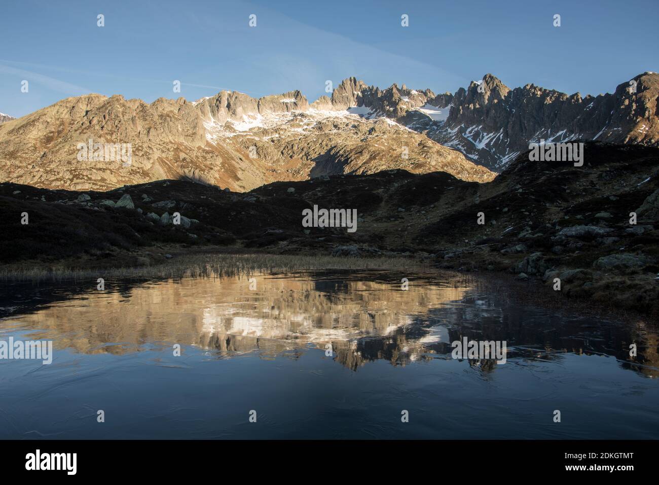 Mountains are reflected in the half-frozen lake Stock Photo