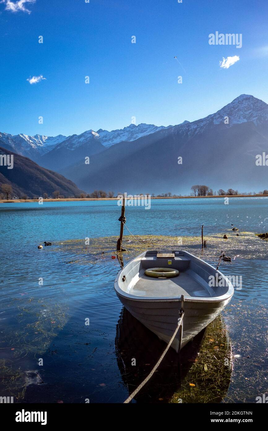 Sailboats Moored On Lake By Mountains Against Blue Sky Stock Photo