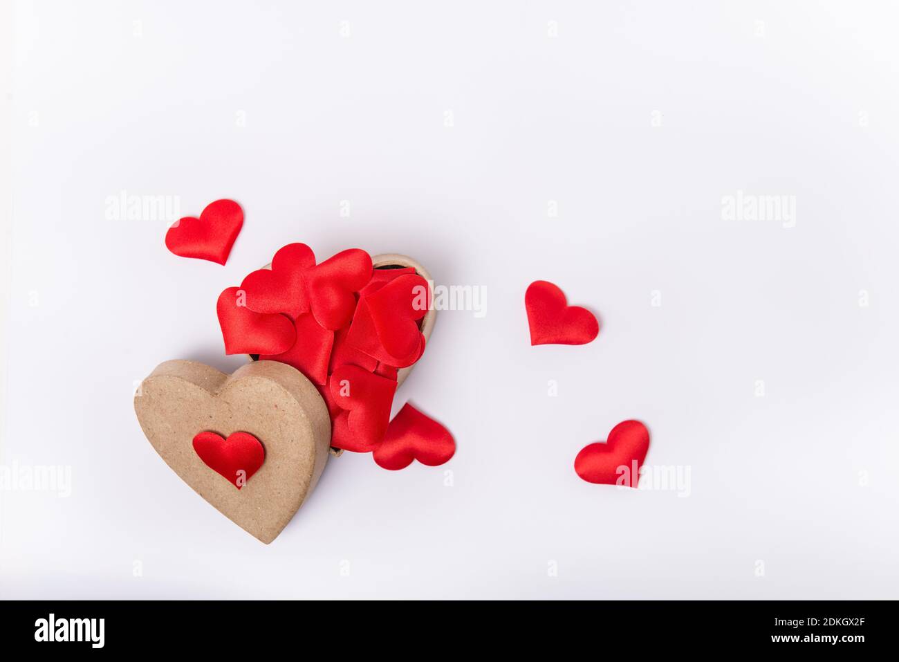 Top View heart-shaped box full of red fabric hearts on the white background. Valentine's day background. Gathering likes concept. Flat lay. Selective Stock Photo
