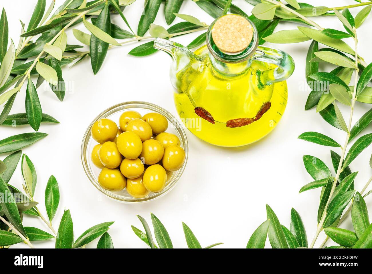 A bottle of olive oil and some olives in a glass bowl on the white ...