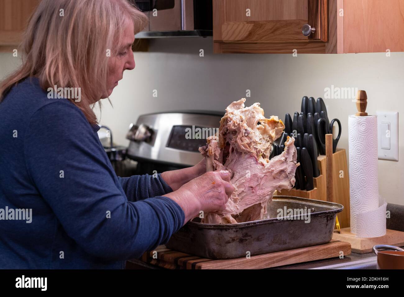 Baby boomer woman concentrates on deboning a Thanksgiving turkey in a