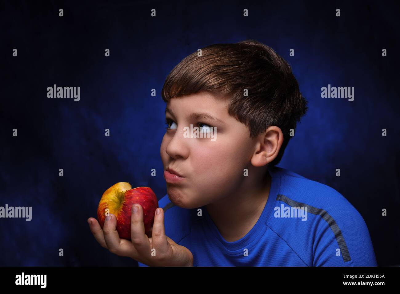 big red-yellow apple in the hand of eating it European teenage boy with ...