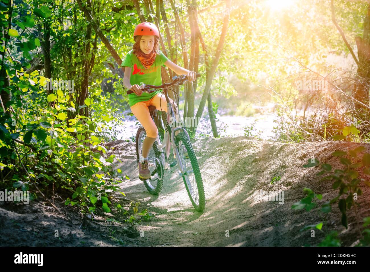 Italy, Veneto, Belluno, Agordino, little girl ( 10 years old) has fun with her bicycle along a forest path Stock Photo