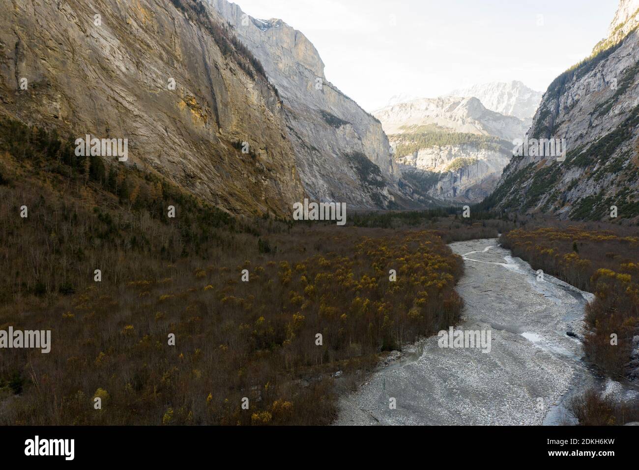 Flat valley framed by steep rocks, river bed in late autumn Stock Photo
