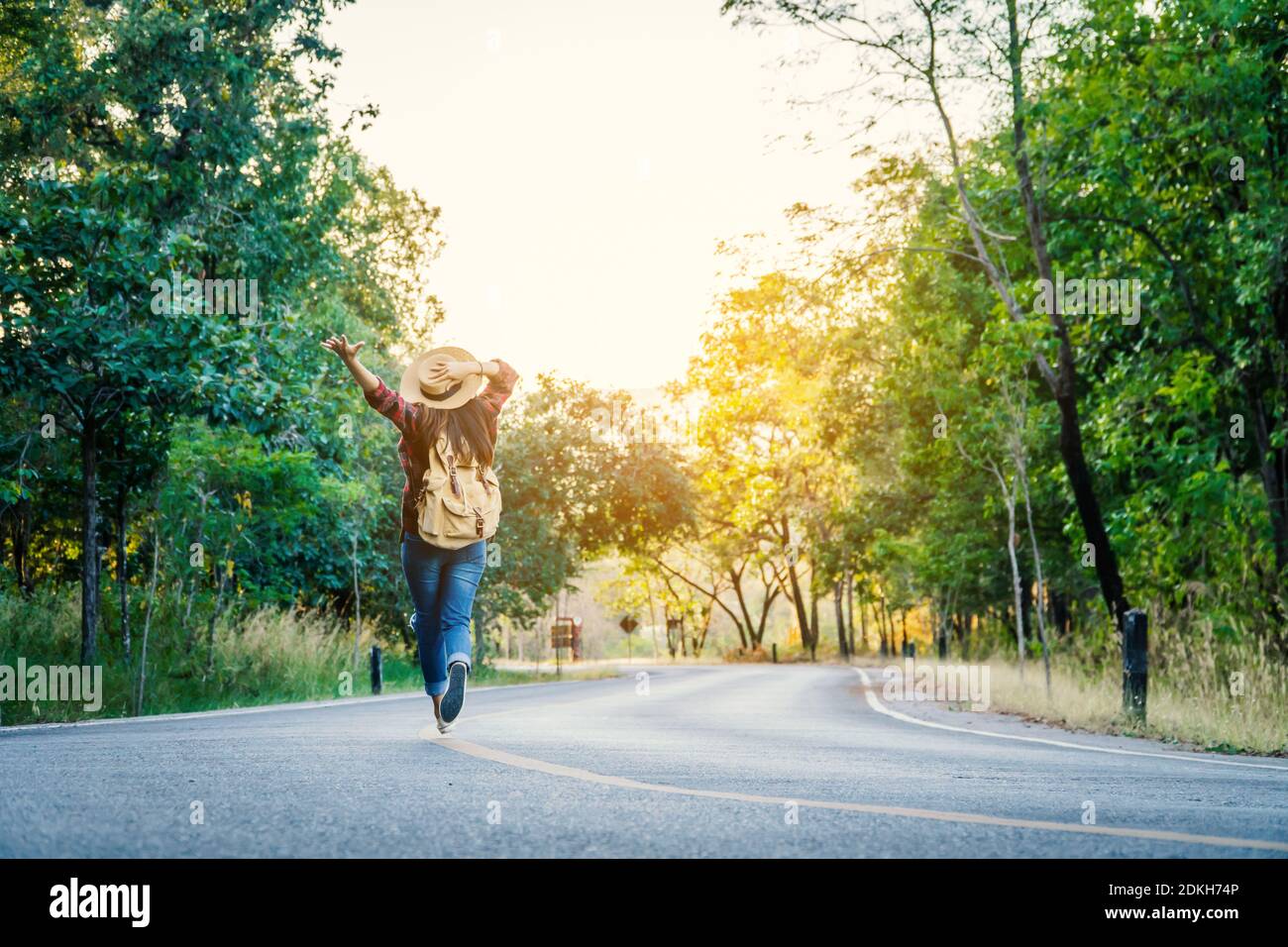 Rear View Of Woman Walking On Road Amidst Trees Stock Photo