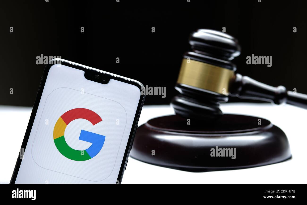 Stafford, United Kingdom - December 15 2020: Google logo seen on the smartphone placed next to the judges gavel. Concept for a lawsuit, legal case, an Stock Photo