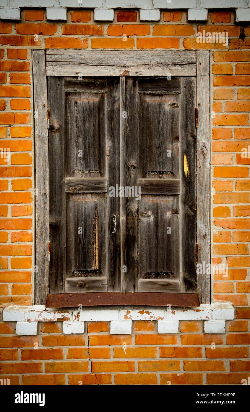 Abstract shuttered window in an old abandoned house witj red brickwork ...