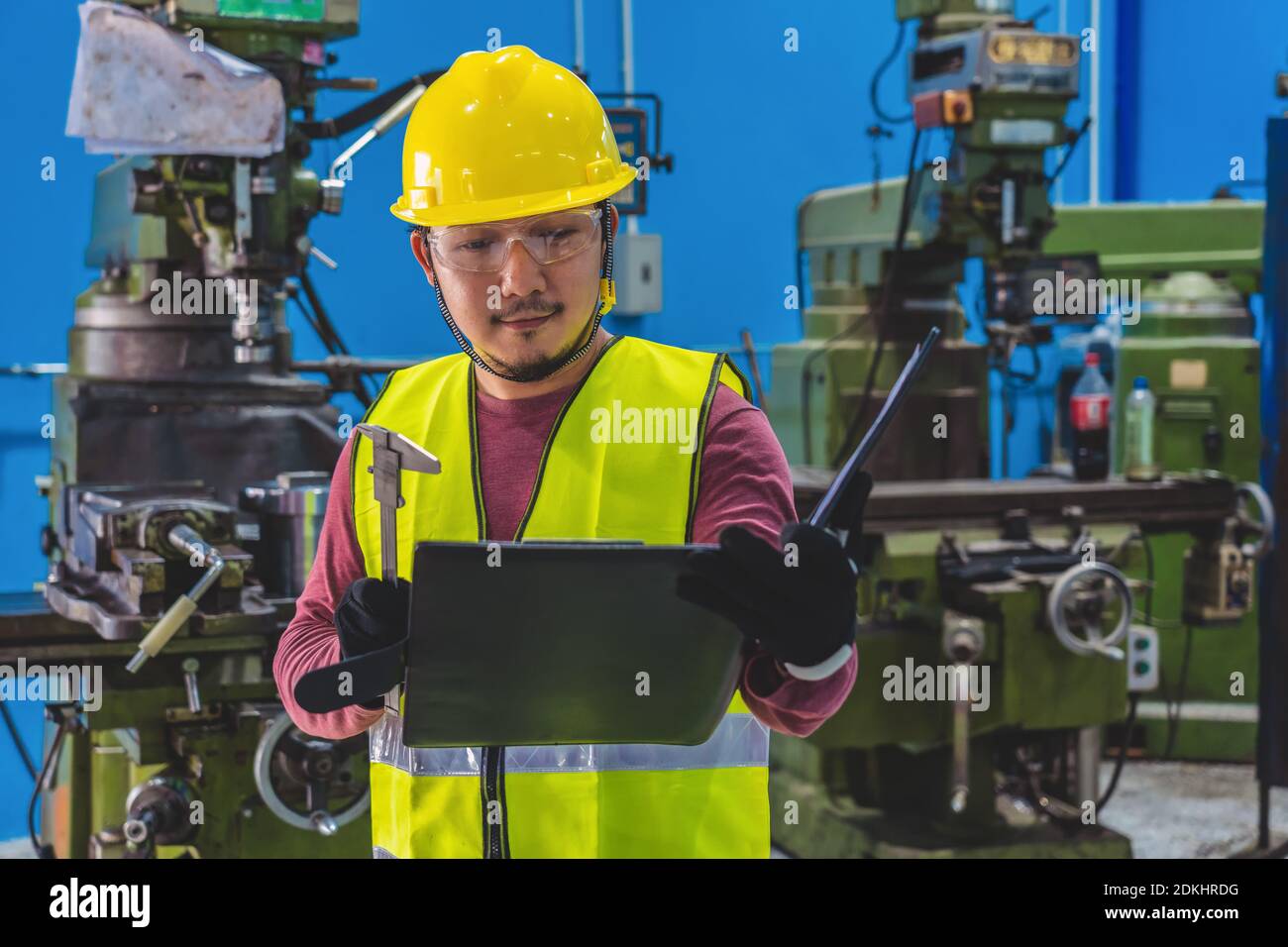 Asian machinist in safety suit checking the the job list with