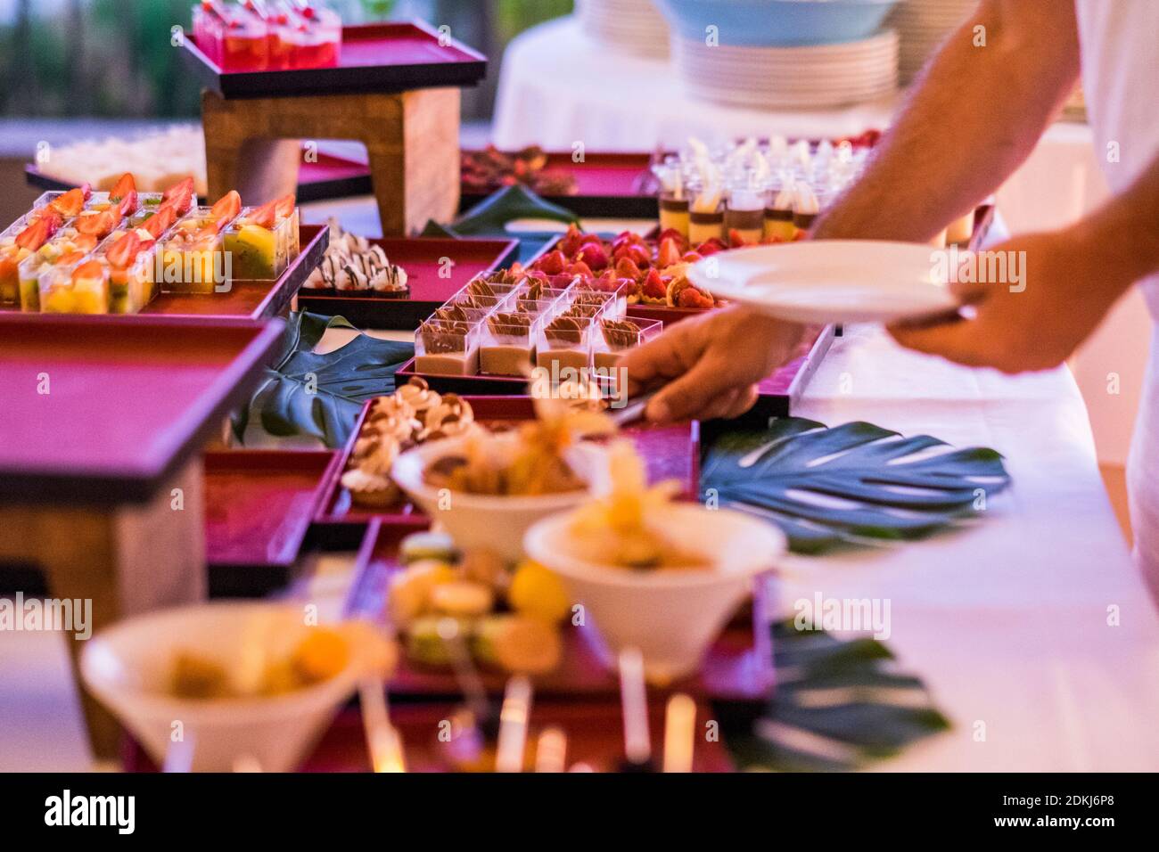 Close up of man serving food in catering table during event - wedding and party concept dinner with cakes and delicious - Stock Photo
