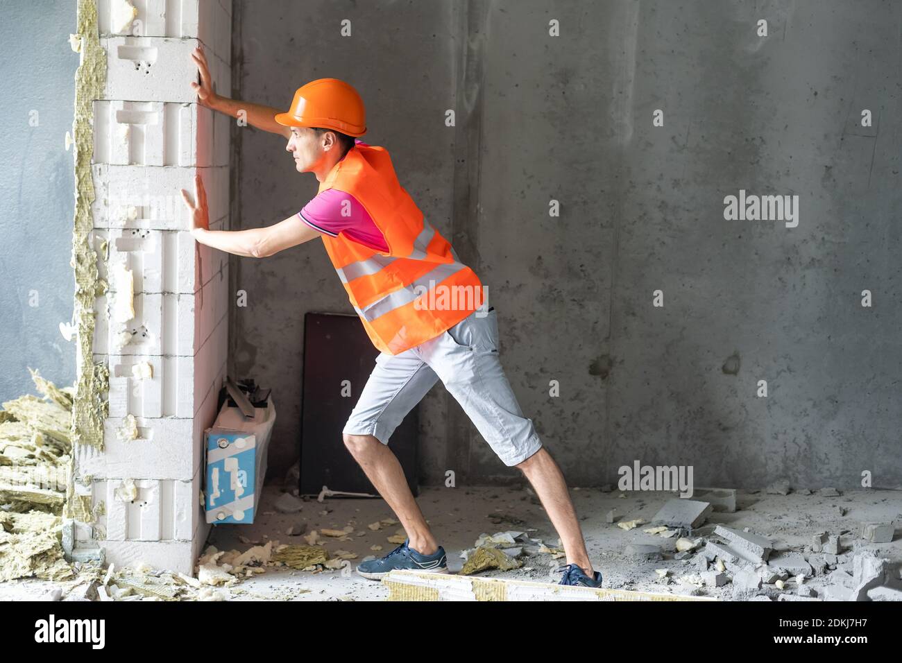 profession, construction and building - happy smiling worker or builder in helmet over room with working equipment at new home or apartment background Stock Photo