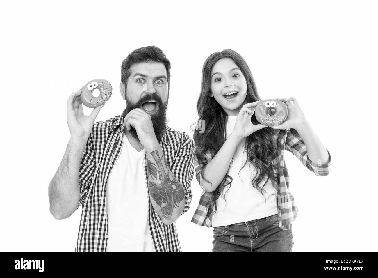 Bakery shop. Fathers day. Sweet tooth. Girl child and dad hold glazed donuts. Cheerful family. Sweets and treats concept. Daughter and father eat sweet donuts. Dessert. Happiness and joy. Sweet mood. Stock Photo