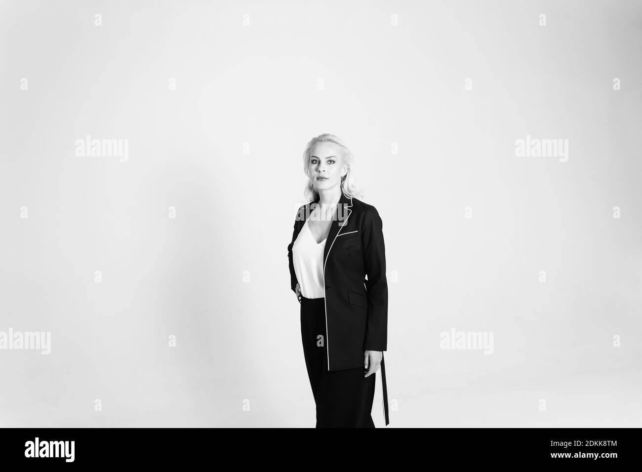Studio Portrait Of Beautiful Blond Woman In A Black Dress Against White Plain Background Stock Photo Alamy