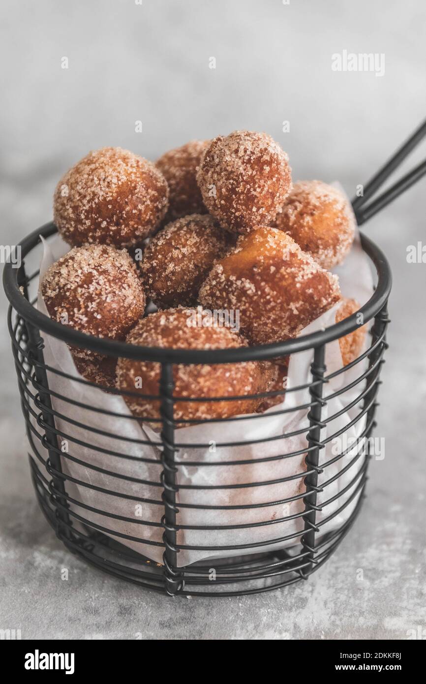 Close-up Of Dessert Donut Holes With Cinnamon Sugar In Container On Comcrete Table Stock Photo