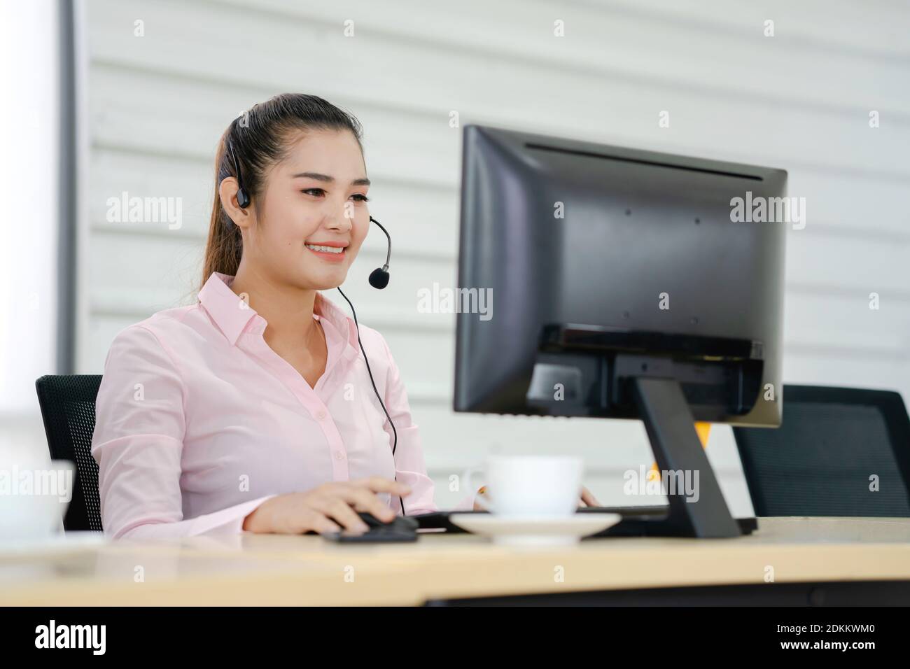 Customer Service Representative Using Computer At Office Desk Stock Photo