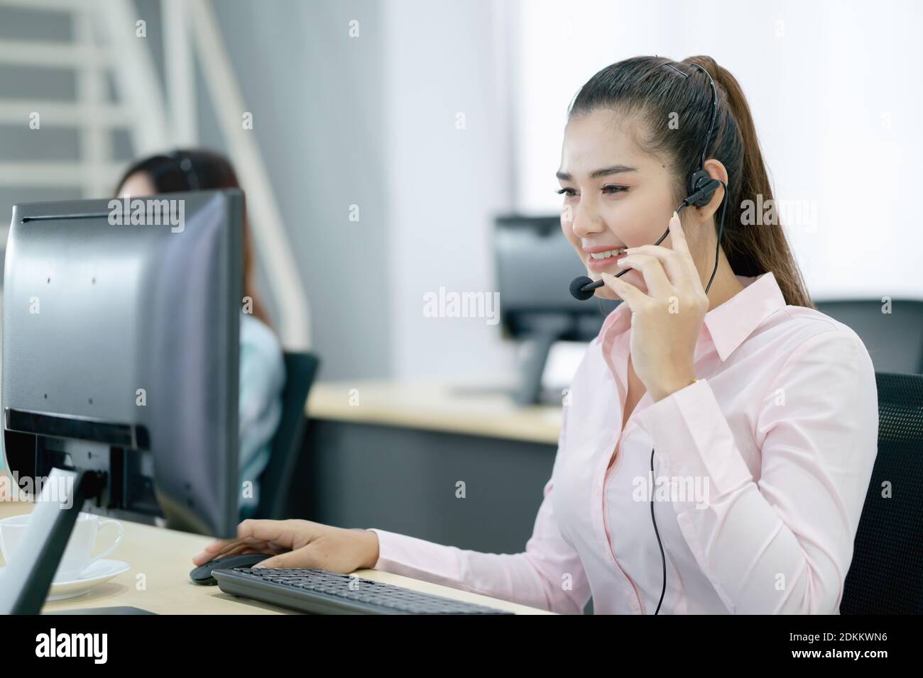Customer Service Representative Using Computer At Office Desk Stock Photo