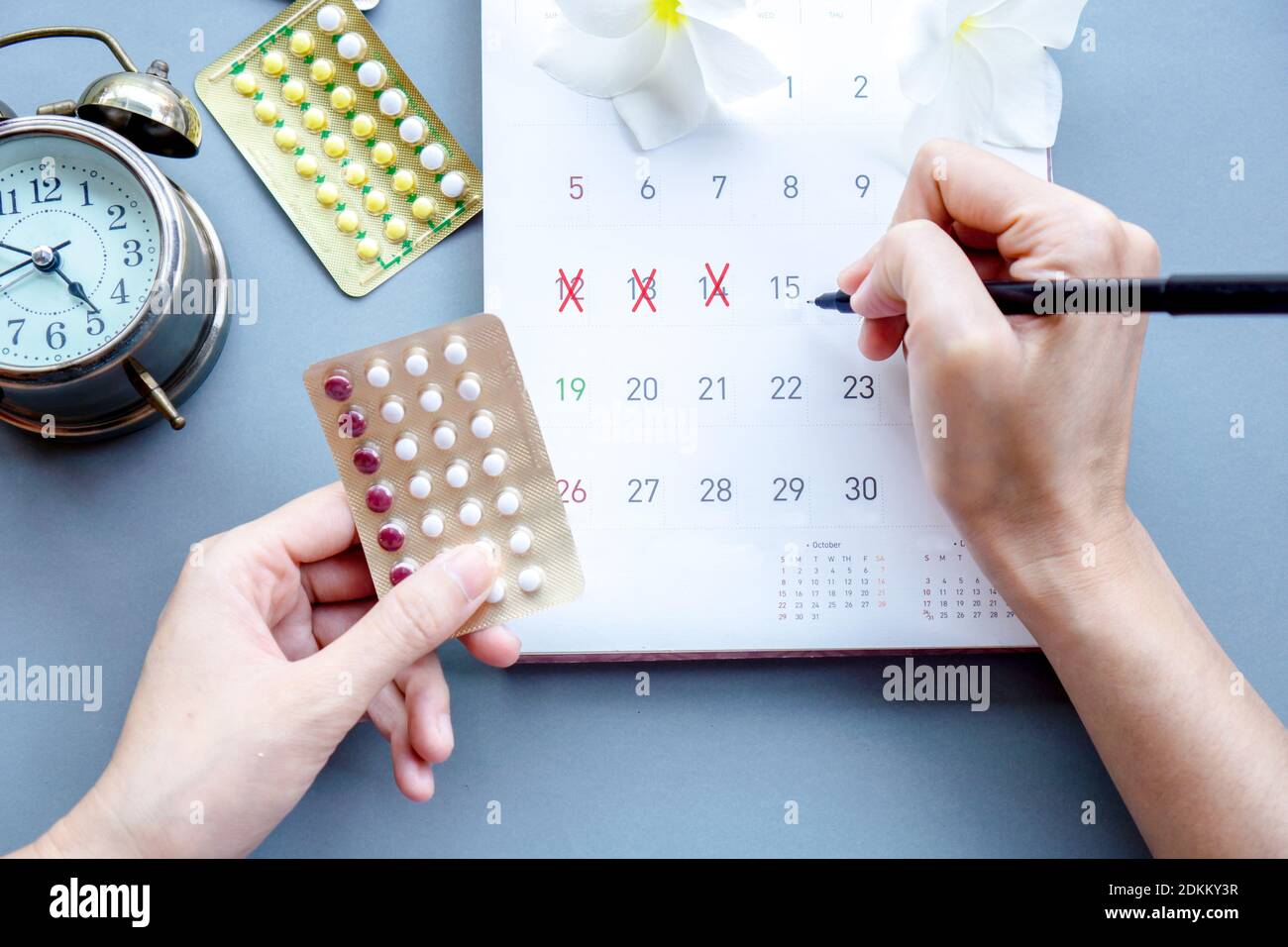 Woman Hand Holding Contraceptive Pills And Mark The Date On Calendar Stock Photo