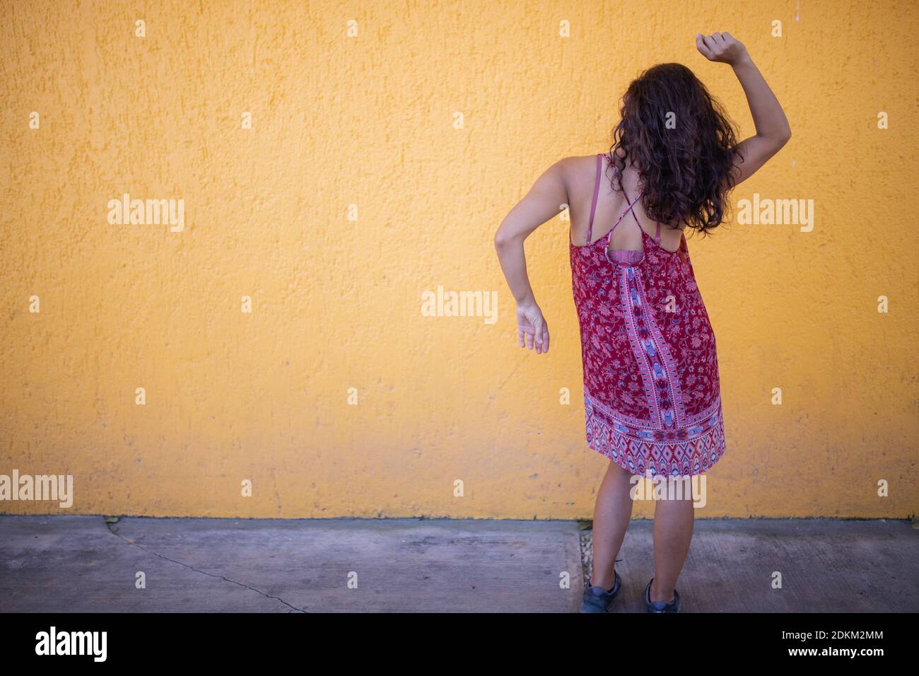 Woman wearing red dress and joyfully dancing in front of a wall Stock ...