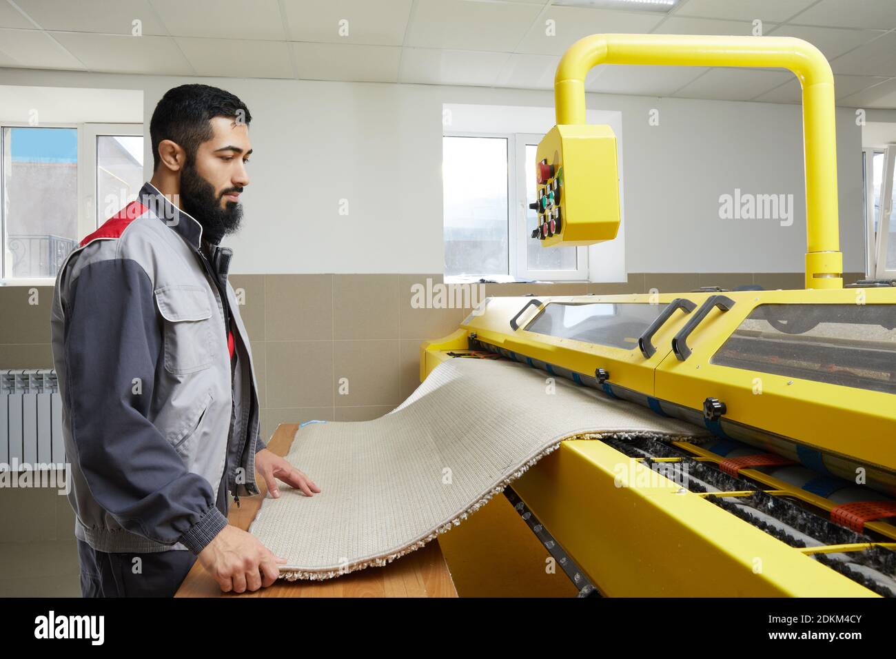 Man operating carpet automatic washing machine in professional laundry service Stock Photo