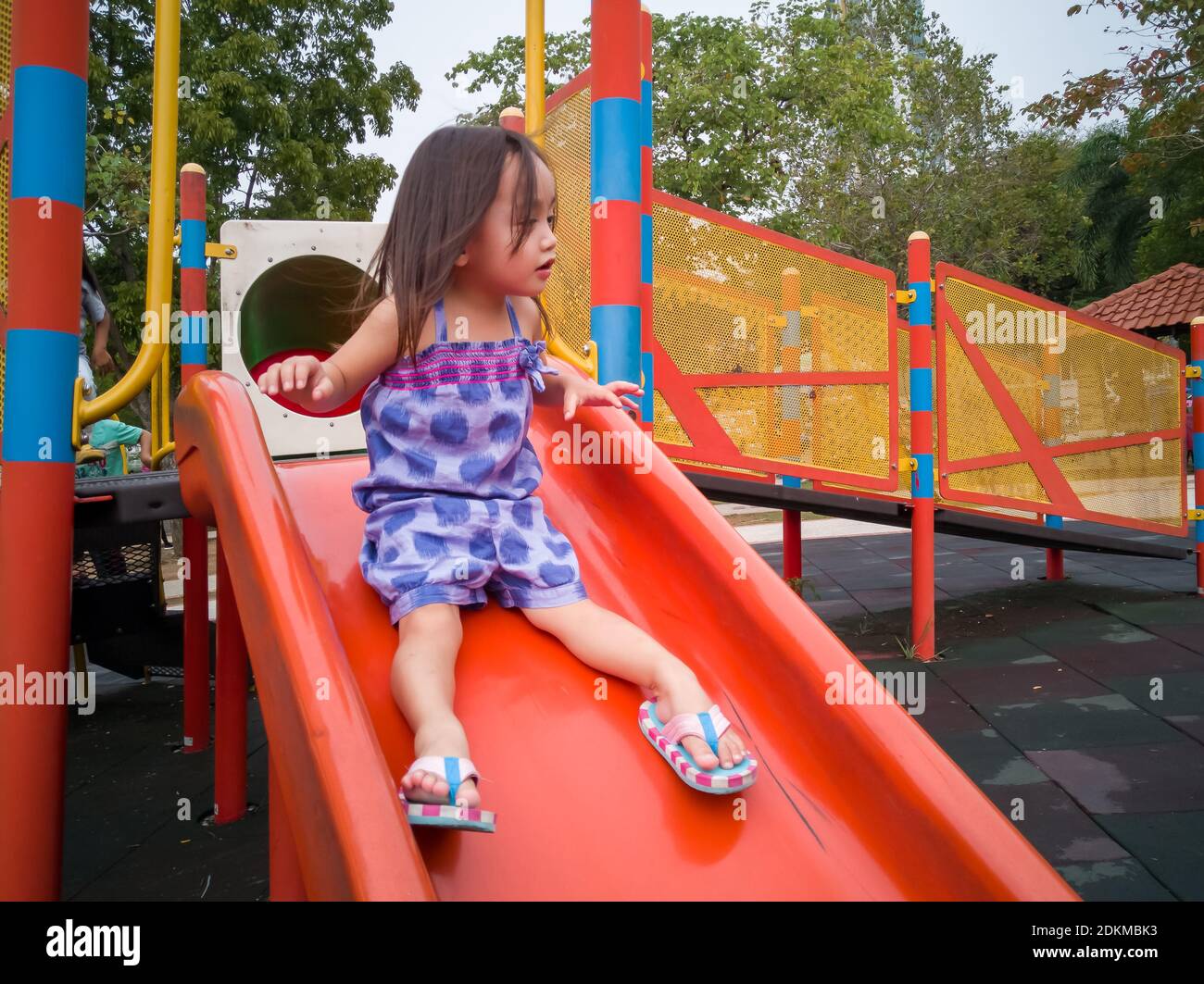 Toddler Girl Playing On A Slide At The Playground Stock Photo