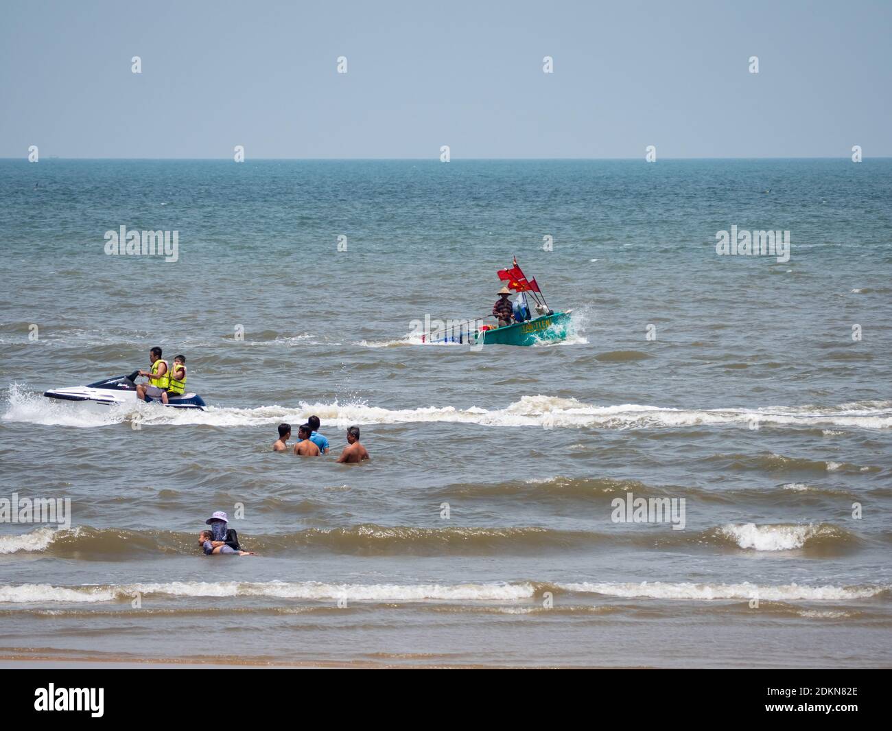 Bai Sau or Back Beach in Vung Tau in the Bang Ria-Vung Tau Province of South Vietnam, with tourists, a watercraft and a round fishing boat, typical fo Stock Photo