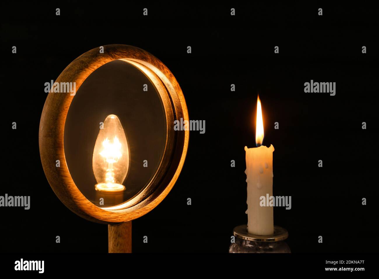 Candle looking at its reflection in mirror on dark background Stock Photo