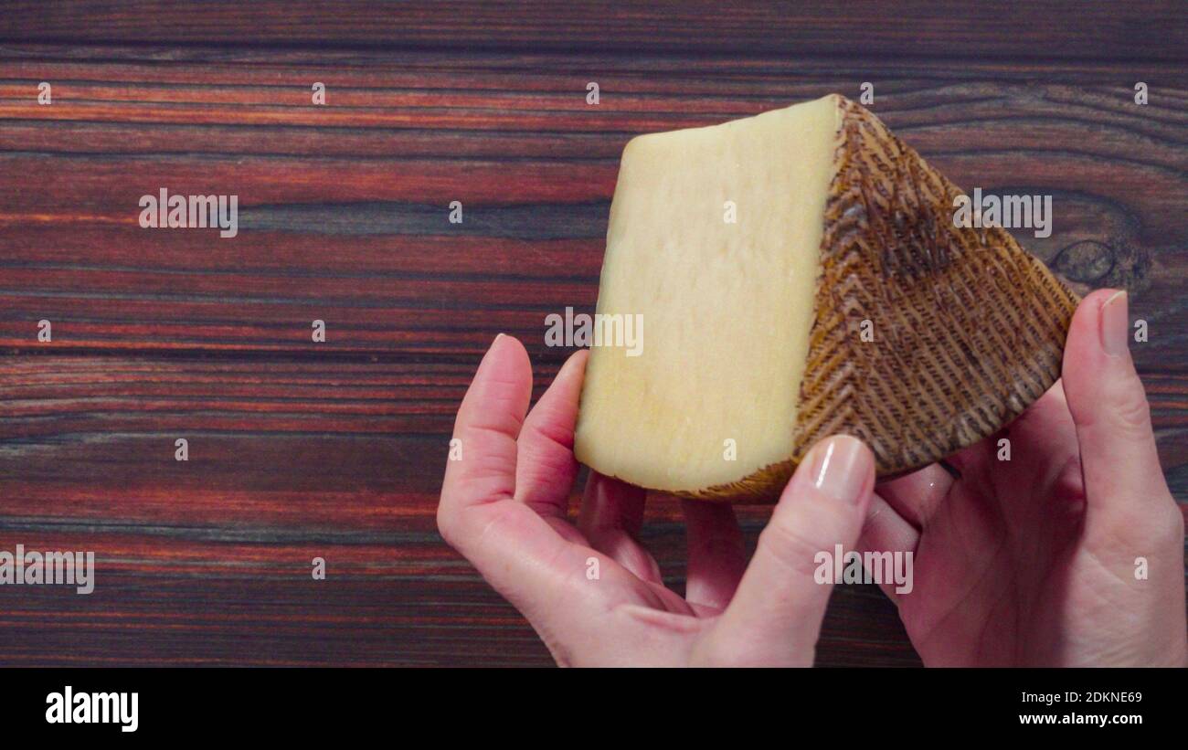 Flat lay. Large wedge of Manchego cheese on a rustic wood background