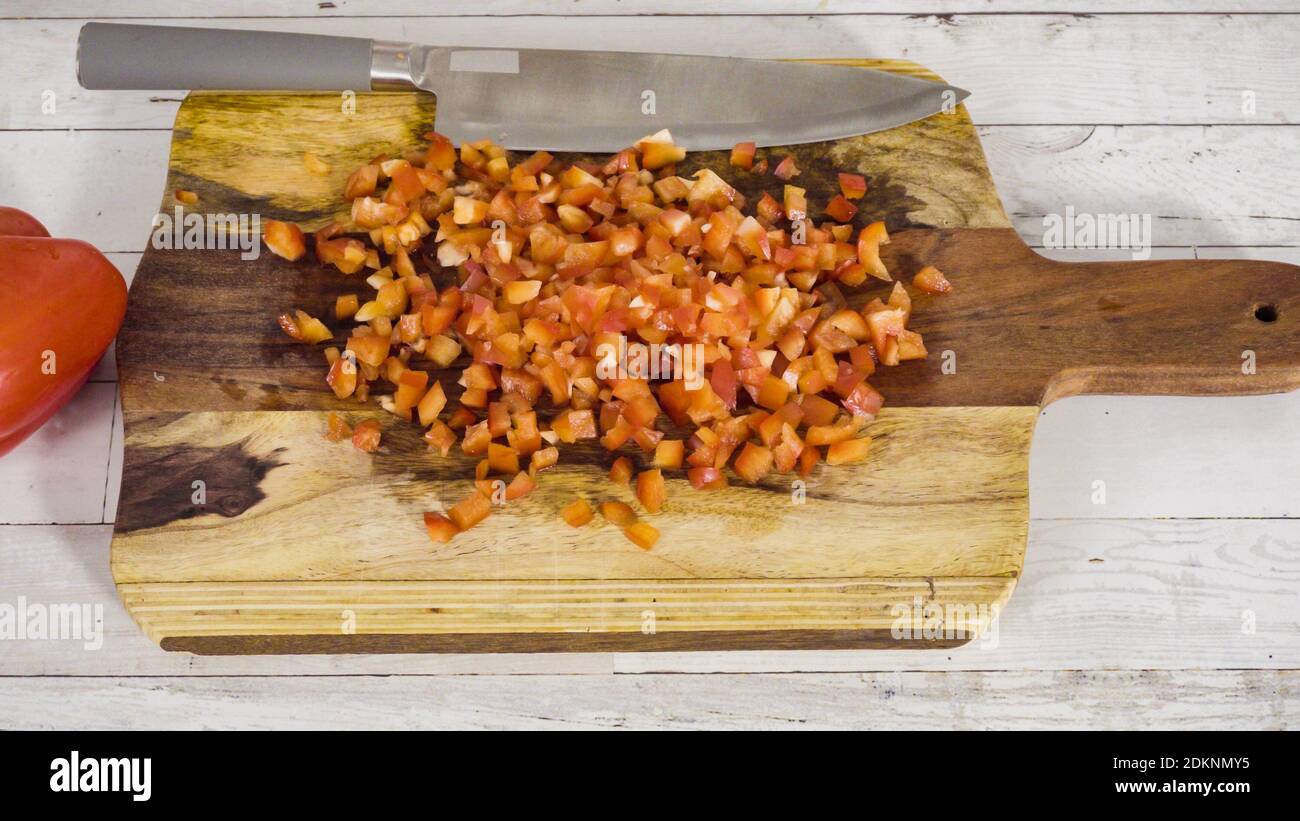 Mincing organic red bell peppers on a wood cutting board Stock Photo ...