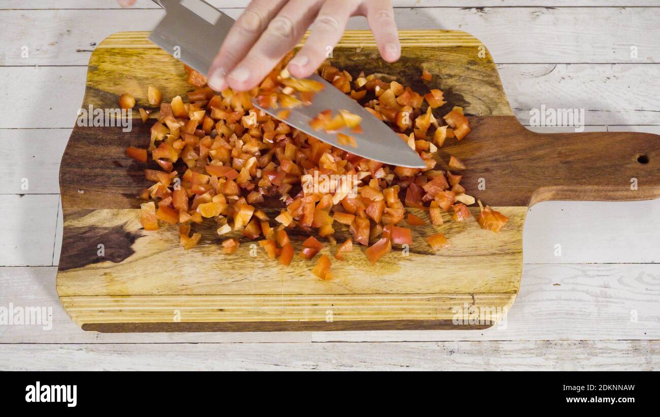 Mincing organic red bell peppers on a wood cutting board Stock Photo ...