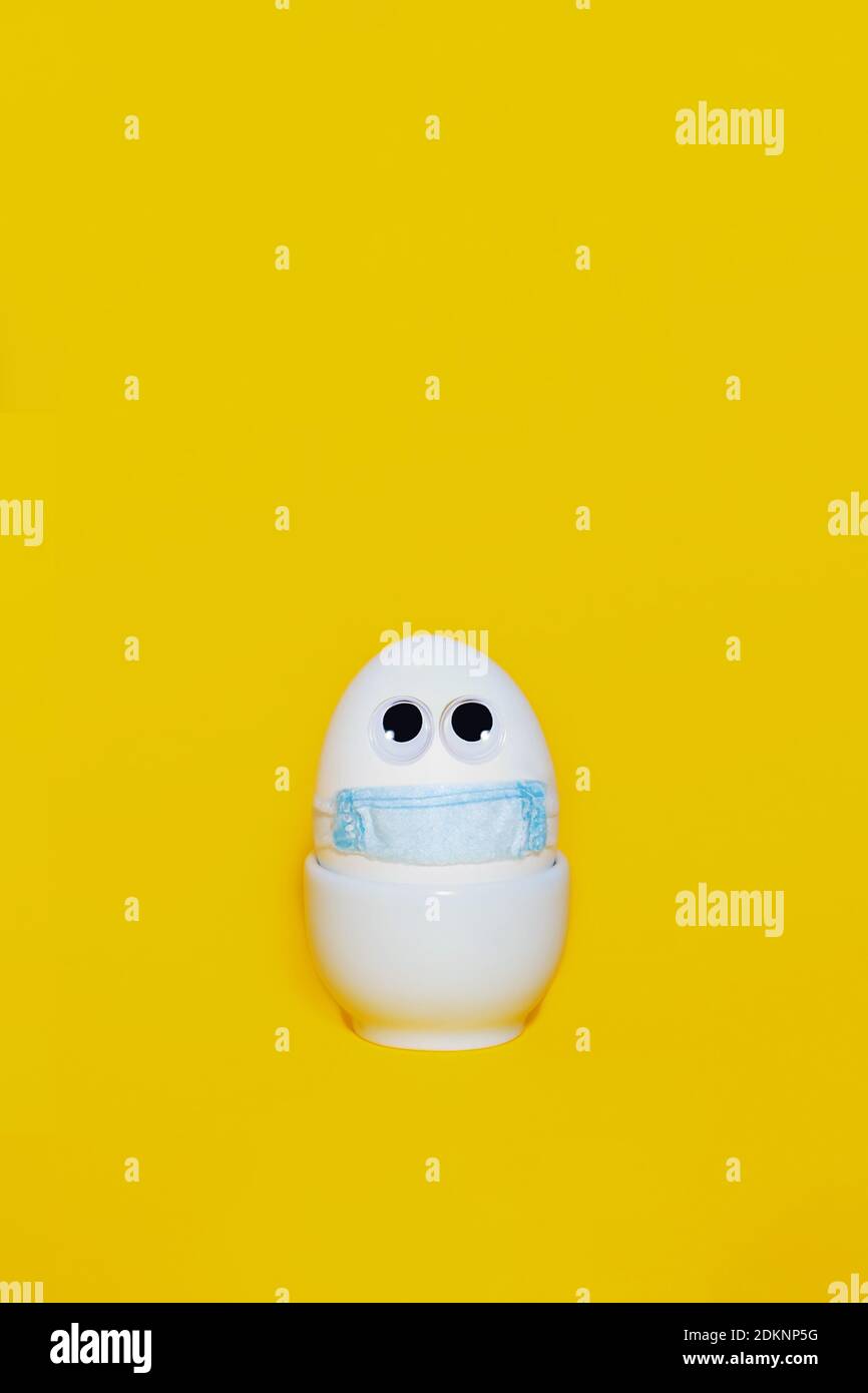 Easter in new reality. Corona virus protection concept. Creative easter idea. Egg in real medical mask. S Copy space. Vertical format. Stock Photo