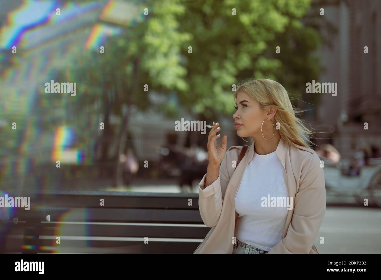Young Woman Smoking Cigarette While Sitting On Bench Stock Photo - Alamy